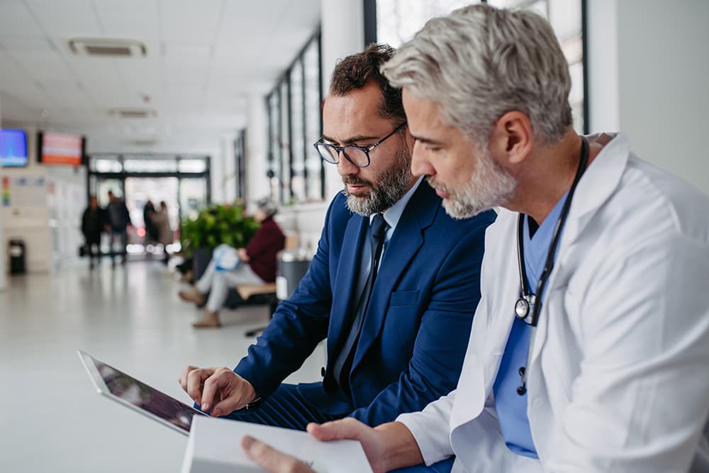 Male doctor reviewing tablet healthcare business program with another man